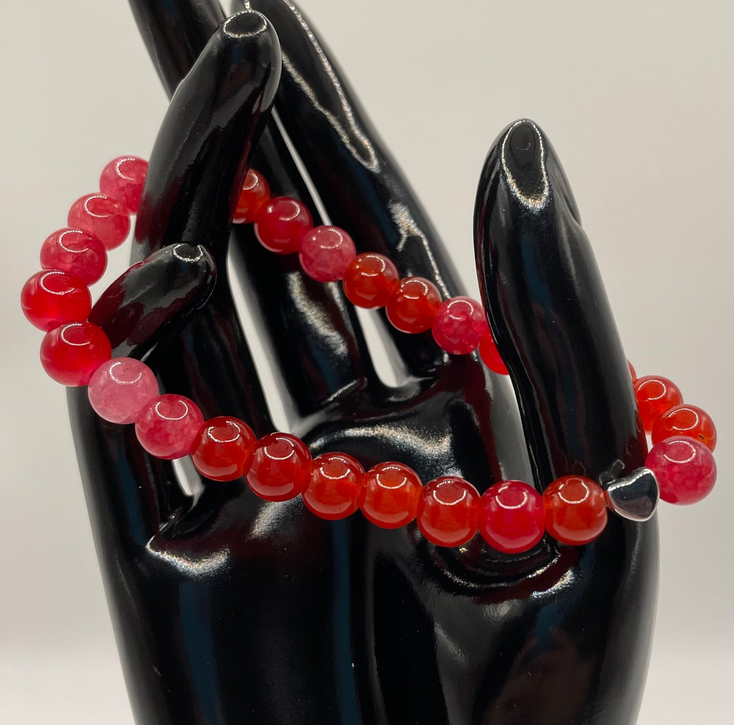 Multi red colored 8mm glass bead bracelet with a metal heart. 7”